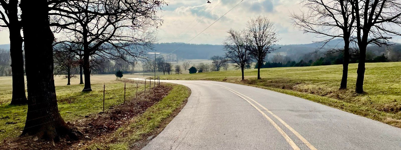 A quiet Fayetteville-area road rolling through green countryside.